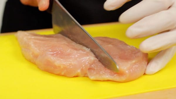 Remove the plastic wrap and cut the chicken in half lengthwise to reduce the cooking time.