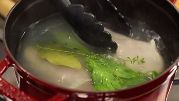Quickly place the chicken into the hot water and place the aromatic leaves onto it.