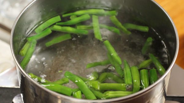When it reaches a full boil, put in the string bean pods, wait for about 30 seconds, and then add the broccoli.