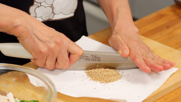 將烤好的白芝麻放在紙巾上，用菜刀切碎。把芝麻切碎，可以散發出美味的香氣，幫助您吸收其中的營養。