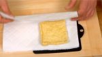 Enveloppez l'aburaage, tofu frit fin, avec de l'essuie-tout et pressez-le avec vos mains. Retournez-le et pressez-le à nouveau pour retirer l'excès d'huile. 