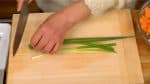 Remove the root part of the spring onion leaves. Stack the leaves together and chop them into fine pieces.