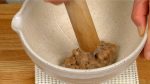 Versez le natto dans un mortier suribachi et pressez-le avec le bout du pilon surikogi.