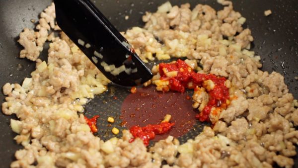 Now, make a space at the center of the pan and add 1 teaspoon of doubanjiang, Chinese chili bean paste. Lightly stir-fry the doubanjiang and bring out the spicy flavor.