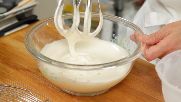 Continue to whip the mixture at a medium speed until the color turns white, and it reaches a soft peak stage. When you lift the mixer, the rippling pattern should remain on the surface as you see here.
