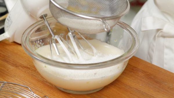 Ensuite, ajoutez la levure chimique à la farine à pain (T65) et mélangez. Puis placez les poudres dans une passoire fine. Et tamisez-les dans le mélange d’œufs. 