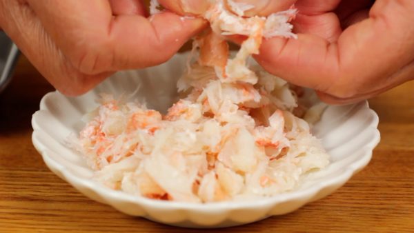 First, let's prepare the crab meat. Flake the crab meat with your fingers. If using canned crab, drain the liquid in a strainer before use.