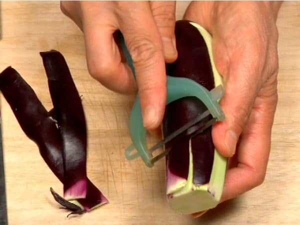 Cut off the stem end of the eggplant and trim off the cap. Partially peel the eggplant in a striped pattern.
