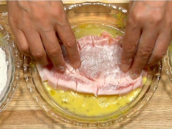 Next, dip the pork in the beaten egg.