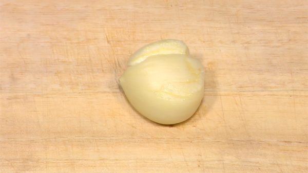 Peel the garlic clove and crush it with the side of the knife.