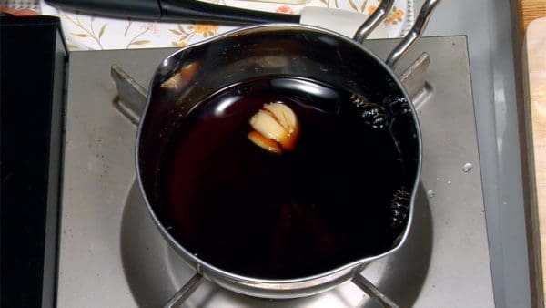 Préparez la sauce yakitori. Ajoutez la sauce soja, le sake, le sucre complet, le miel, et la gousse d'ail dans une casserole. 