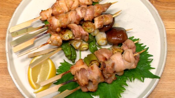 Arrangez les yakitori à la sauce avec des feuilles shiso et les quartiers de citron.