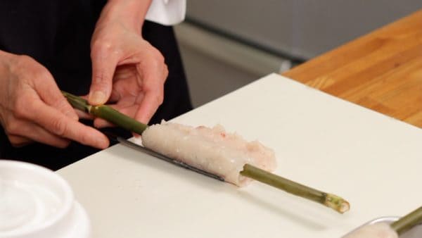Using a spatula, scrape off the surimi from the surface and roll it around the bamboo.