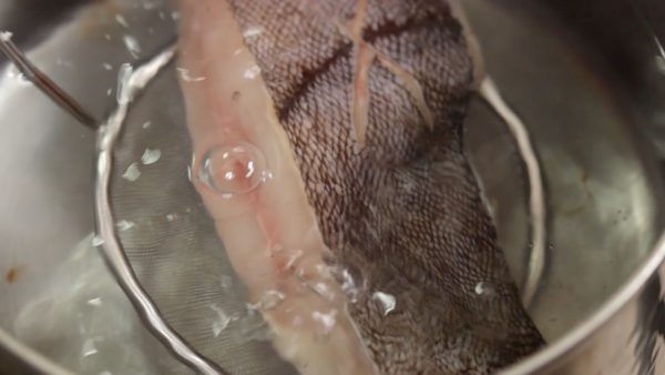 Place the karei fish onto a mesh strainer and submerge it in the hot water.