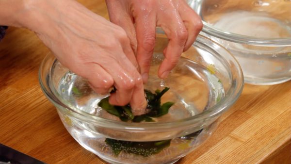 Squeeze and place the wakame into another bowl of water.