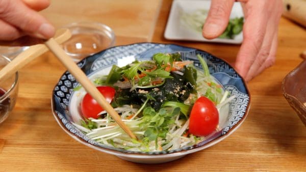Saupoudrez le sésame sur la salade. Décorez avec les tomates et les pousses de radis kaiware ou le cresson.