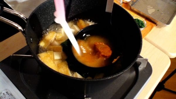 Ensuite, placez le miso dans la louche et placez-la dans la casserole. Ajoutez un peu de bouillon dashi dans la louche et dissolvez le miso dans la louche. Cela va aider à dissoudre complètement le miso.