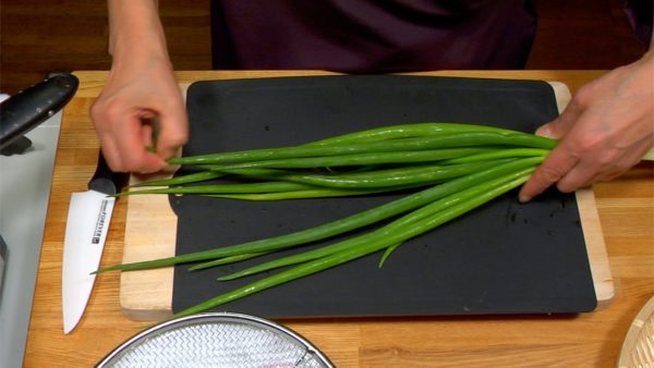 Let's cook the wakegi green onions. Pinch off the tips of the wakegi leaves in order to prevent them from bursting wide open in the boiling water.