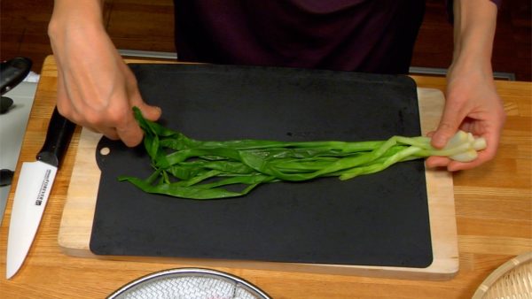 Arrange the wakegi on the cutting board with their root ends aligned.