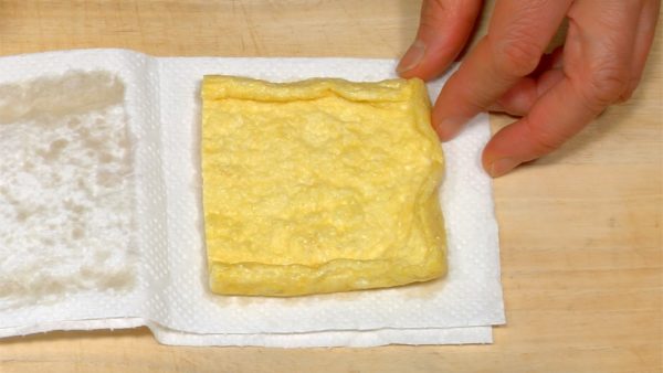 Let's toast the aburaage, deep-fried thin slice of tofu. Press the aburaage against the paper towel and remove the excess oil.