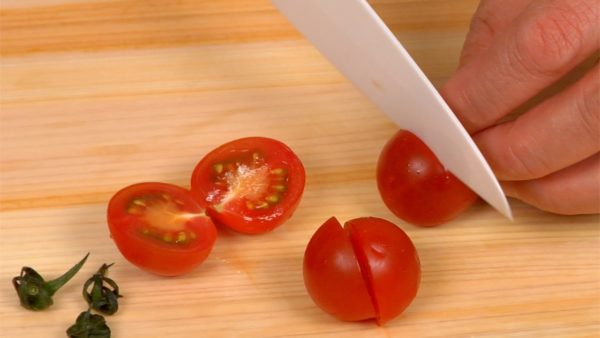 Remove the stems from the tomatoes, cut them in half and place in the bowl.