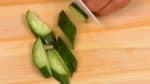 Coupez le concombre en deux dans la longueur, coupez-le en tranches diagonales de 3mm (0.1 inch), et placez les tranches sur la salade.