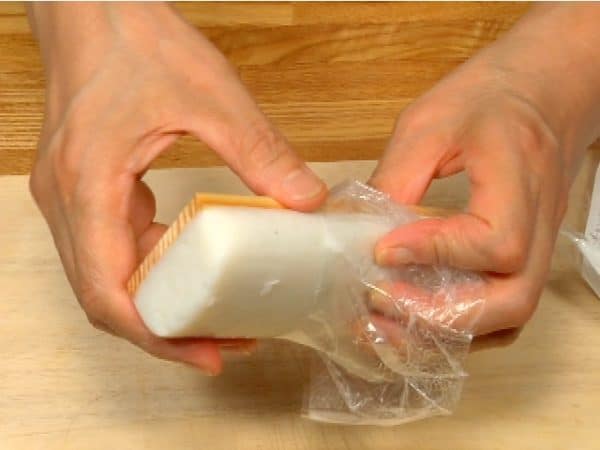 Remove the outer wrap from kamaboko fish cake. Strip the inner wrap halfway.