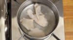 Placez les ailes de poulet dans l'eau bouillante. Mélangez doucement avec des baguettes de cuisine.