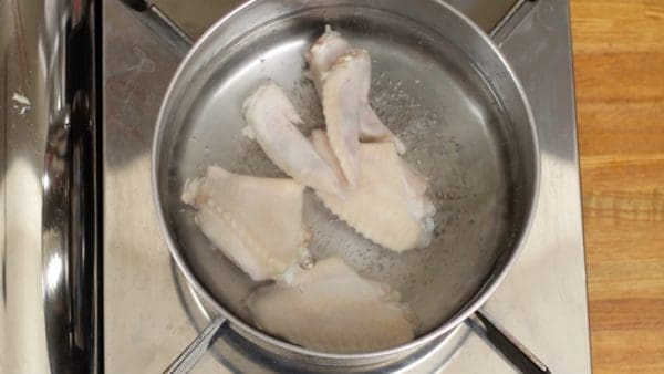 Place the chicken wings in boiling water. Lightly stir with kitchen chopsticks.