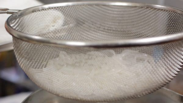 Strain the noodles and hit the strainer against a kitchen towel several times to remove the excess water thoroughly.