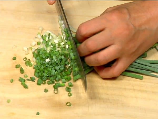 Cut the spring onion leaves into three pieces. Chop them into fine pieces.