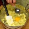 Schlage das Ei in eine Schale auf. Füge nur das Eigelb zur Kartoffelmischung und rühre es gut unter.