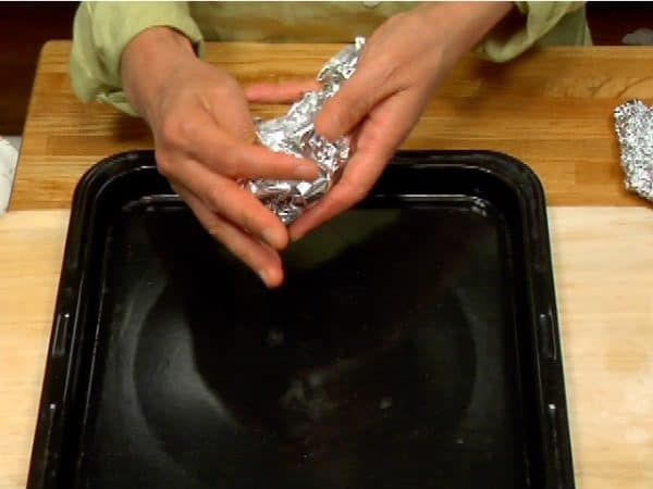 讓我們製作烤番薯的支撐底。將一張鋁箔捲成枕頭狀。