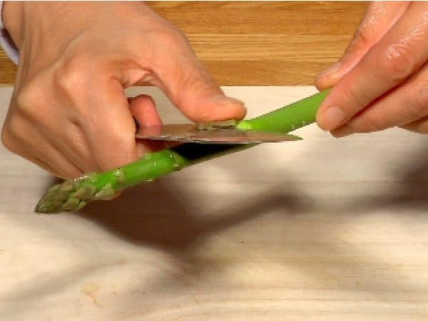 Remove the tiny scales from the asparagus and cut the asparagus spear in half.
