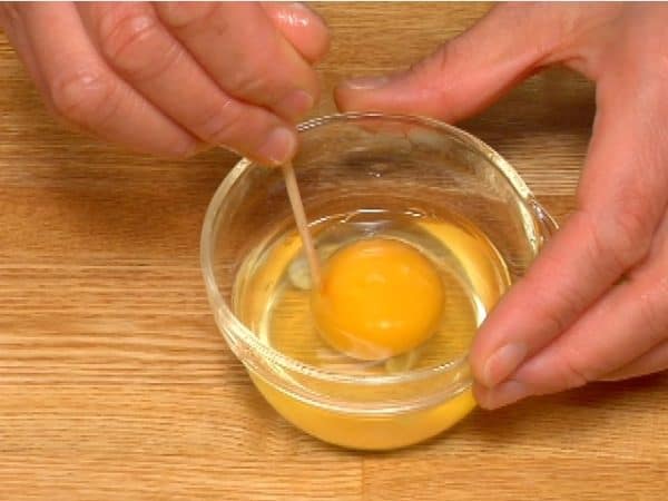 Let's make a soft boiled egg using a microwave oven. Crack the egg into a small microwave-safe bowl. To prevent the egg from bursting, pierce the yolk with a bamboo stick in 3 to 4 places.