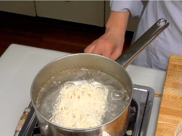 Drop the frozen udon noodles into a large pot of boiling water.
