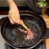 Plongez la tranche fine de bœuf dans le bouillon mijoté et secouez-la dedans plusieurs fois.