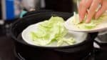 把包菜葉放在盤子裡。包菜會吸收燒賣中的任何汁液，使它們更美味。