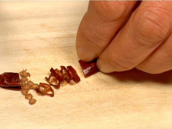 Remove the seeds from the dried red chili pepper and slice the pepper into rings.