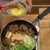 Dip the ingredients in the egg and enjoy the delicious sukiyaki. 