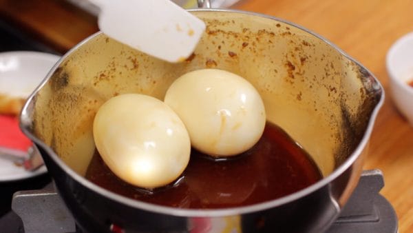 Gib die gekochten Eier mit der verbliebenen Soße in den Topf.