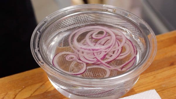 Lightly rinse the thinly sliced red onion to soften the pungency. Remove and strain it with a mesh strainer.