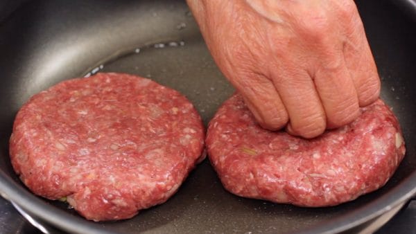 Place the meat patties onto the pan and lightly press to make them firmly attached. Gently, so as not to create any cracks in the surface of the meat.