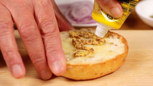 Spread the whole grain mustard on the bottom of the buns.