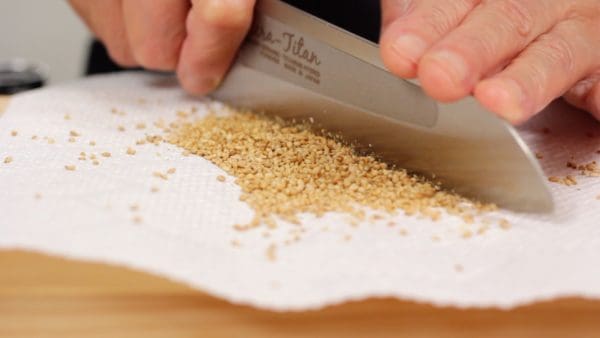 Then, transfer the sesame seeds to a cutting board covered with a paper towel. Roasting and chopping the sesame seeds makes them much more fragrant. It also gives the sesame a different texture from ground sesame.