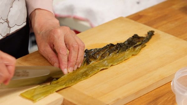 Next, let's chop the takanazuke, a pickled takana leaf. Separate the thin leafy part from the thick midrib part in the middle.