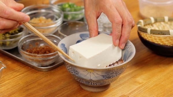 Chill the smooth, silken tofu thoroughly, lightly drain and place it onto the rice.