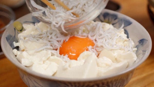 Arrange a generous amount of kamaage shirasu around the yolk. Kamaage shirasu is salt-boiled young sardine fish that have about 80% water content. It is moister and softer than other types of shirasu. Sprinkle finely chopped pickled takana around the shirasu.