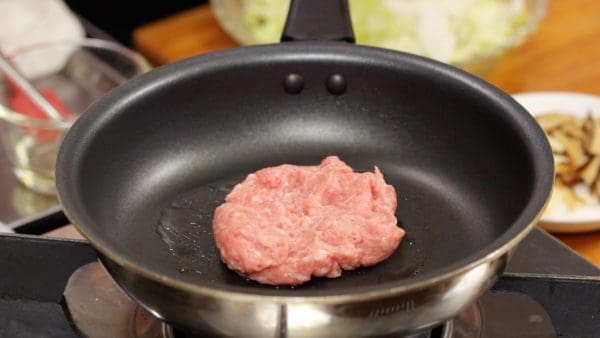 Next, let's make the filling. Put a moderate amount of vegetable oil in a heated pan. Add the seasoned ground pork and begin cooking while separating the meat.