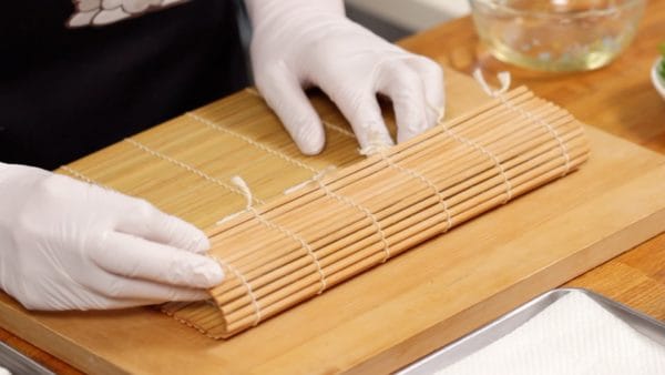 Bây giờ, chúng tôi sẽ làm cơm cuộn Tekkamaki. Để tấm tre dùng làm cơm cuộn (sushi) với mặt phẳng, mềm hướng lên trên.